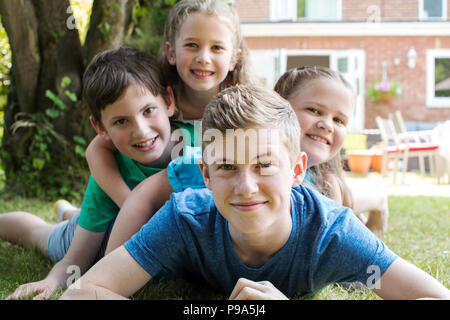 Portrait Of Four Brothers And Sisters Lying In Garden At Home Stock Photo