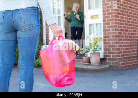 Close Up Of Woman Doing Shopping For Senior Neighbor Stock Photo