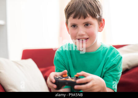 Boy Sitting On Sofa At Home Playing Computer Game Stock Photo