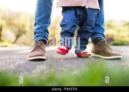 First steps of a toddler girl outside in spring nature. Stock Photo