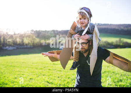 Happy toddler boy and father playing with wings outside in spring nature. Stock Photo