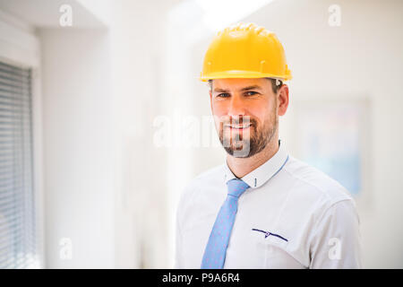 A young engineer or architect with white shirt, tie and helmet in a room. Stock Photo