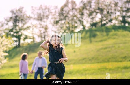 A small girl with grandparents on a walk outside in spring nature. Stock Photo