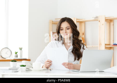 Happy young business woman or secretary holding document in modern office Stock Photo