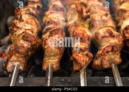 Close up of just roasted hot pieces of meat and onion on few metal skewers on top of metal brazier full of hot charcoal.  This barbecue and picnic dis Stock Photo