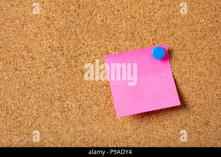 Business concept. Pink sticky note with blue pushpin and blank space, isolated on cork background. Stock Photo