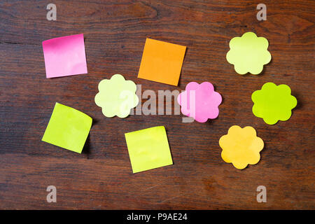 School concept. Sticky colorful notes in various shapes with copy space on wooden background. Stock Photo