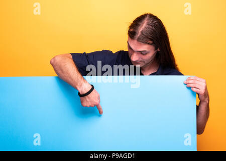 Man looking down while pointing at cardboard banner Stock Photo