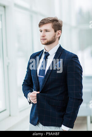 businessman in a business suit stands near the window, hands fol Stock Photo