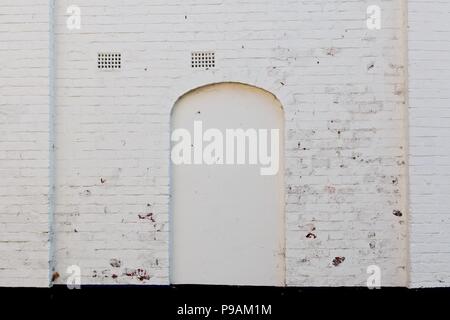 Old white whitewashed wall with briked up doorway door Stock Photo