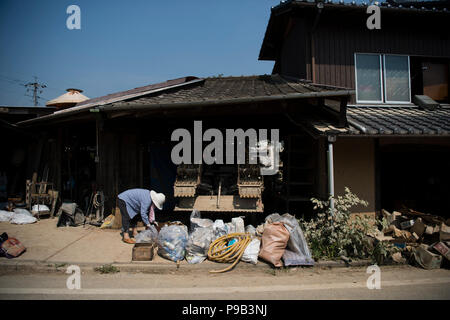 Okayama, Japan. 17th July 2018. A resident cleans up at a home damaged by flooding in Mabicho, Kurashiki, Okayama Prefecture, Japan. More than 200 people died in floods and landslides caused by torrential rains more than a week ago. On Sunday, the government announced the weather event would be designated an extremely severe disaster, freeing up recovery funds for the affected areas. Cleanup and recovery efforts have been hampered by extreme heat. Credit: Aflo Co. Ltd./Alamy Live News Stock Photo