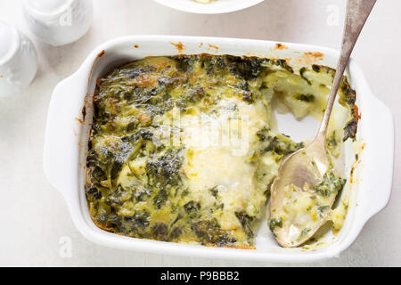 Potato and spinach gratin in creamy garlic sauce Stock Photo