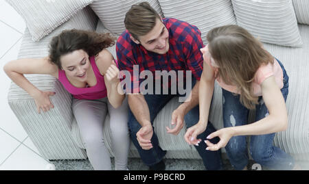 triumphant group of friends laughing while sitting on the couch in the living room Stock Photo