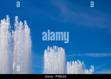 Tops of large fountain jets gushing upwards against blue sky, may be used as background Stock Photo