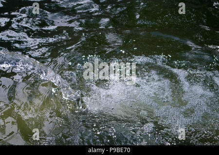 Boiling and foaming bubbled water falling down from the jet in a large fountain reservoir Stock Photo