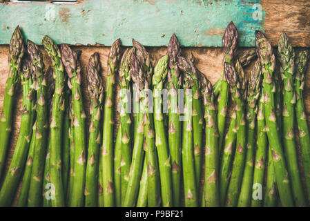 Raw uncooked green asparagus over rustic wooden tray background, close-up Stock Photo