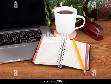 Opened notebook and pencil with a laptop computer on a wooden desktop Stock Photo