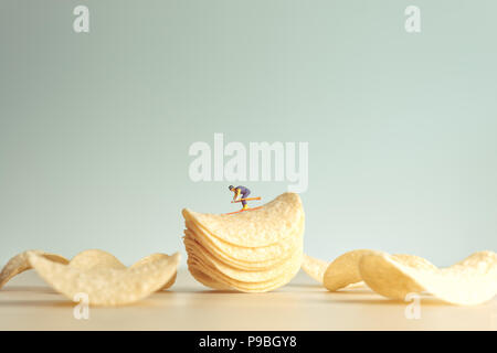 Miniature skier skiing down potatoe chips. Stock Photo