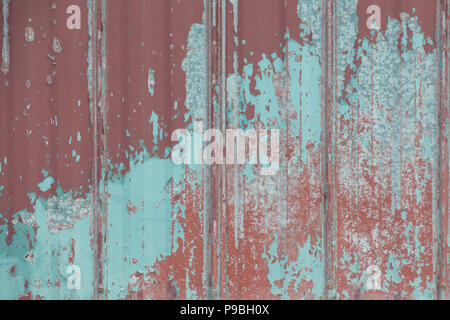 Faded peeling rusty steel sheets with oxblood red paint. Grunge, distressed, weathered and worn, galvanized panels. Stock Photo