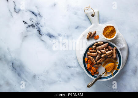 roots of turmeric and powder from it on a white marble board and table. healthy natural supplements, spices for cooking Stock Photo
