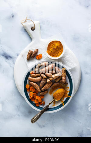 roots of turmeric and powder from it on a white marble board and table. healthy natural supplements, spices for cooking Stock Photo