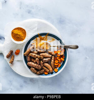 roots of turmeric and powder from it on a white marble board and table. healthy natural supplements, spices for cooking Stock Photo