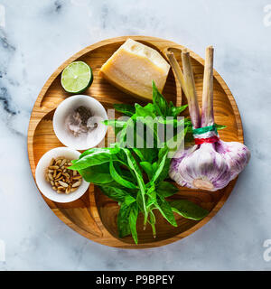 fresh ingredients for cooking Italian classic green pesto basil sauce. with pine nuts, garlic and parmesan cheese. on a white marble table Stock Photo