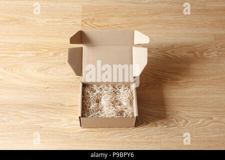 Opened cardboard box with wood excelsior shred filler on wooden background. View above Stock Photo