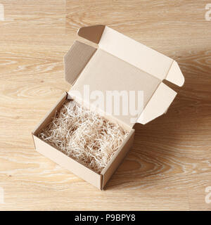 Opened cardboard box with wood excelsior shred filler on wooden background. View above Stock Photo