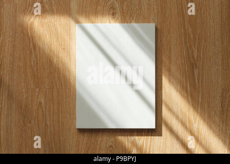 Blank canvas with portrait orientation on wooden wall in sun rays Stock Photo