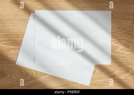 Two blank sheets of paper on wooden background in sun rays Stock Photo