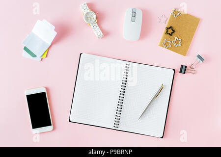 Women workplace concept. Open notepad and personal accessories on pink background, flat lay top view Stock Photo