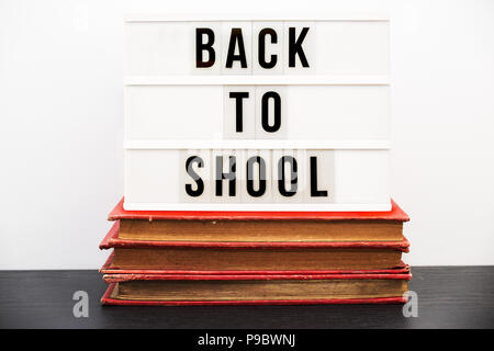 Back to school written in a light box on top of a pile of old  books Stock Photo