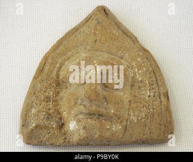 Roman antefix. Vertical block which terminates the covering tiles of the roof. High-imperial era. Roman antefix. High-imperial era. Male head, covered by a cucullus. National Archaeological Museum. Tarragona. Catalonia, Spain. Stock Photo