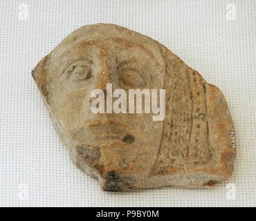 Roman antefix. Vertical block which terminates the covering tiles of the roof. High-imperial era. Male head with mouth half open. He is carrying a cucullus. National Archaeological Museum. Tarragona. Catalonia, Spain. Stock Photo