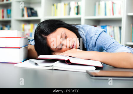 Tired student sleeping in library Stock Photo
