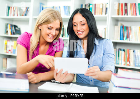 Students learning in library, using digital tablet Stock Photo