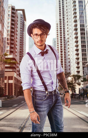 Young man in hat, glasses, bow-tie and suspenders looking at camera Stock Photo
