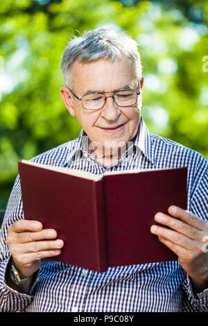 Senior man reading a book in park Stock Photo