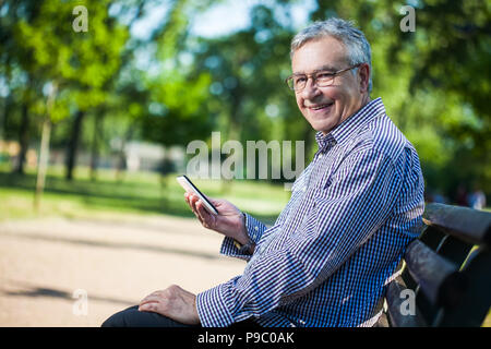 Senior man using digital tablet in park Stock Photo