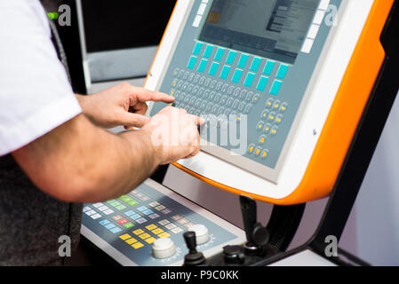 Man working on a keyboard of a console for controlling an industrial machine. Man's hands on a control panel Stock Photo