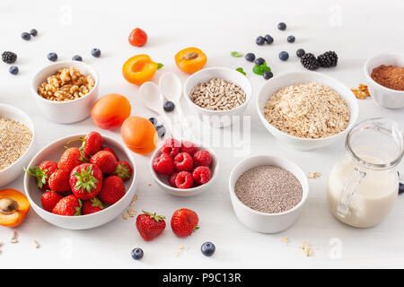 variaty of raw cereals, fruits and nuts for breakfast. Oatmeal flakes and steel cut, barley, walnut, chia, apricot, strawberry. Healthy ingredients Stock Photo