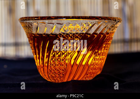 colored liquid in a fancy decorative cut glass bowl backlit by a small electric candle. Stock Photo
