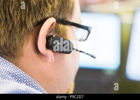 Man in call centre working with a telephone earpiece Stock Photo