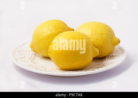 Three lemons in a plate on white background Stock Photo