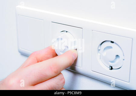 Inserting Baby Safety Plugs Into Wall Socket To Prevent Danger At Home Stock Photo