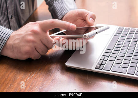 A Businessman Working With Mobile Phone And Laptop In Office, Side View Stock Photo