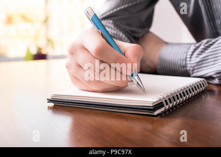 Front View Of A Man In Business Shirt Writing In A Blank Notepad With A Biro Stock Photo