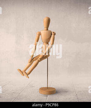 Wooden mannequin posed in front of a greyish background Stock Photo