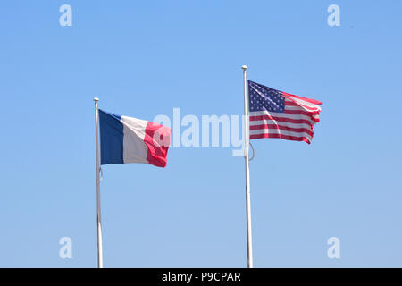 French and American flags flying together against a blue sky. Stock Photo